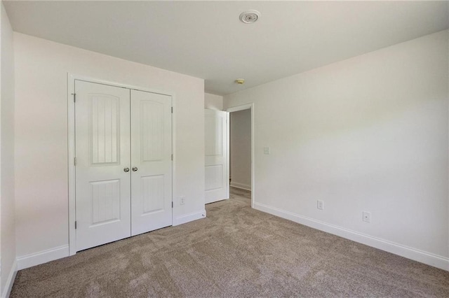 unfurnished bedroom with light carpet and a closet