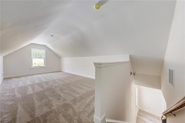 additional living space with vaulted ceiling and light carpet