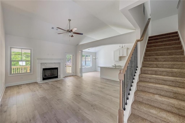 unfurnished living room featuring ceiling fan, plenty of natural light, vaulted ceiling, and light hardwood / wood-style flooring