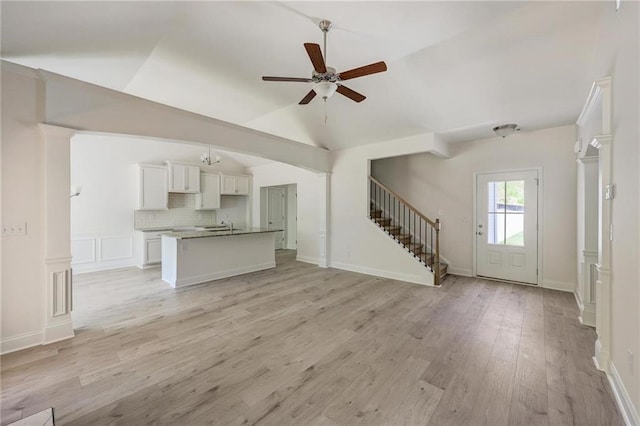 unfurnished living room featuring sink, vaulted ceiling, light hardwood / wood-style floors, and ceiling fan