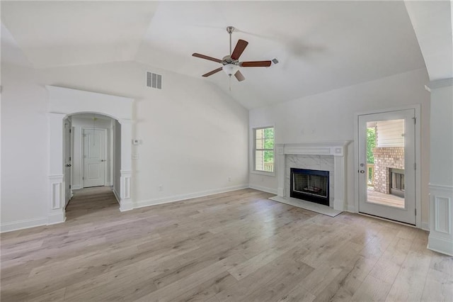 unfurnished living room with lofted ceiling, plenty of natural light, light hardwood / wood-style floors, and a premium fireplace