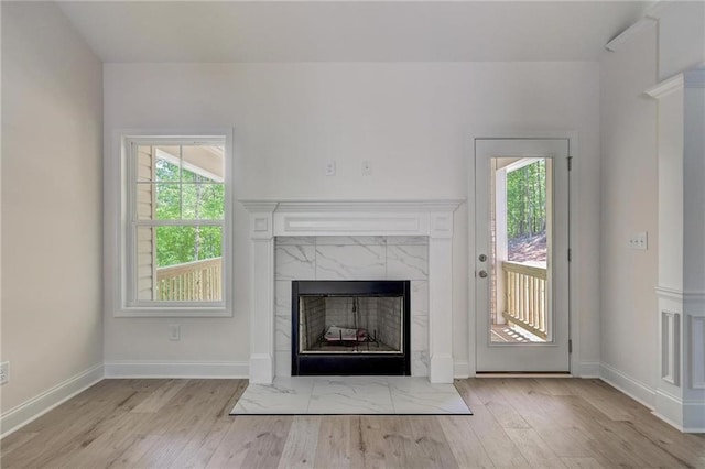 unfurnished living room with a high end fireplace and light wood-type flooring