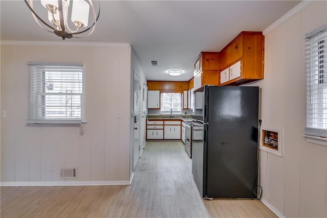 kitchen with black fridge, plenty of natural light, crown molding, and light hardwood / wood-style floors