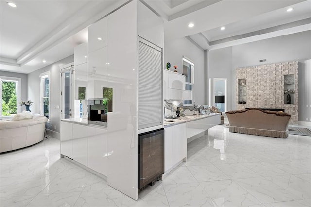 full bath with a freestanding tub, recessed lighting, a high ceiling, marble finish floor, and a tray ceiling