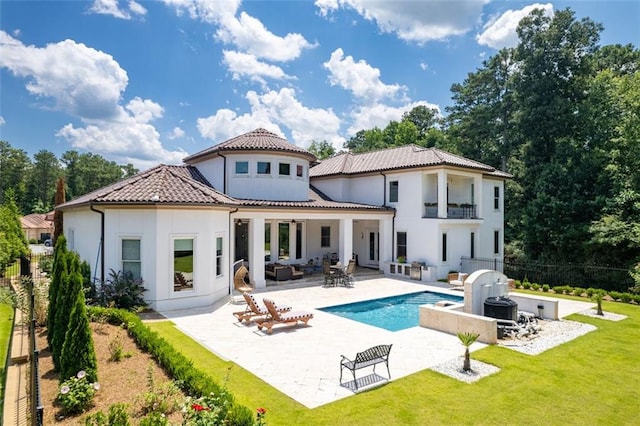 rear view of property featuring a fenced in pool, a tile roof, a yard, a patio, and stucco siding