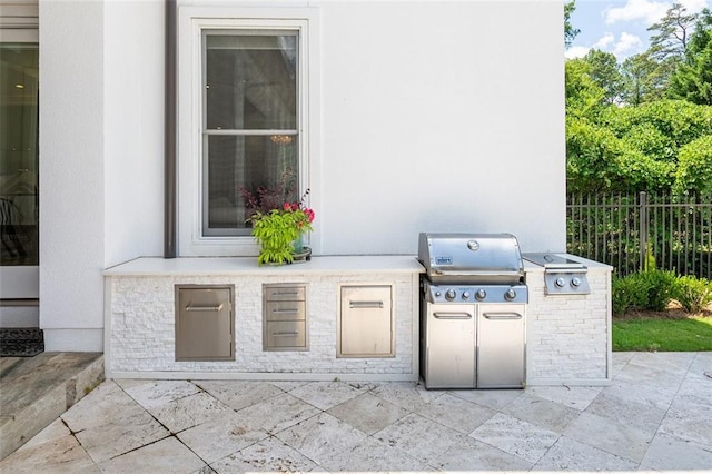 view of patio / terrace with exterior kitchen, grilling area, and fence