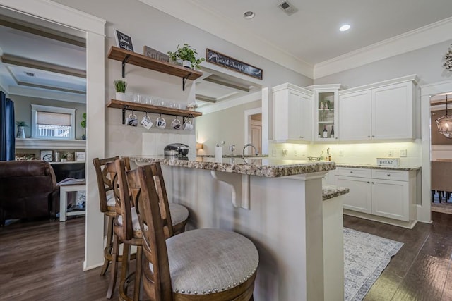 kitchen featuring white cabinetry, light stone counters, a kitchen bar, dark hardwood / wood-style flooring, and kitchen peninsula