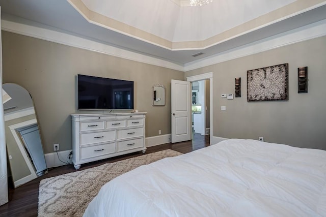 bedroom featuring dark hardwood / wood-style flooring, ornamental molding, and a raised ceiling