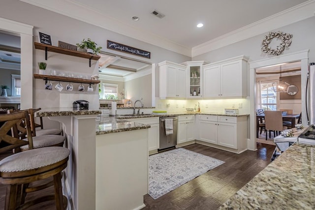 kitchen featuring appliances with stainless steel finishes, white cabinets, a kitchen bar, light stone counters, and kitchen peninsula