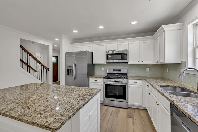 895 Roxfield Ct, Buford, GA 30518 - kitchen featuring appliances with stainless steel finishes, a sink, white cabinets, light wood-style floors, and ornamental molding