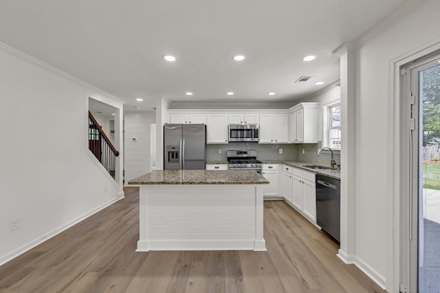 895 Roxfield Ct, Buford, GA 30518 - kitchen with appliances with stainless steel finishes, a sink, a kitchen island, light wood-type flooring, and dark stone countertops