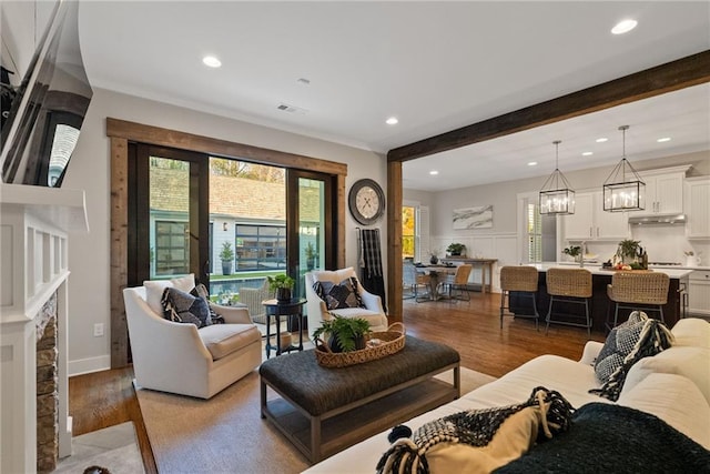 living area featuring beam ceiling, recessed lighting, light wood-style floors, and visible vents