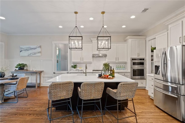 kitchen with visible vents, ornamental molding, stainless steel appliances, an inviting chandelier, and light countertops