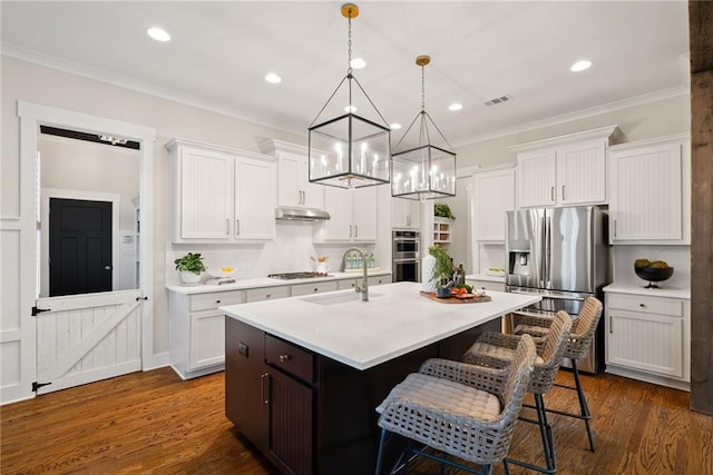 kitchen with a sink, appliances with stainless steel finishes, ornamental molding, and light countertops