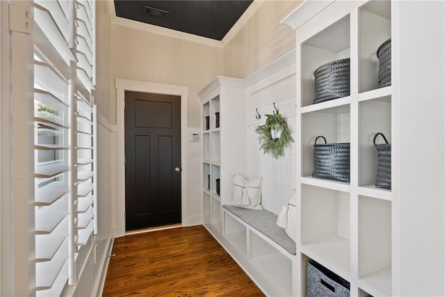 mudroom with a towering ceiling, visible vents, dark wood finished floors, and crown molding