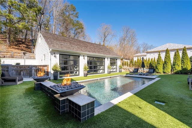 back of house featuring a yard, fence, an outdoor structure, and an outdoor fire pit