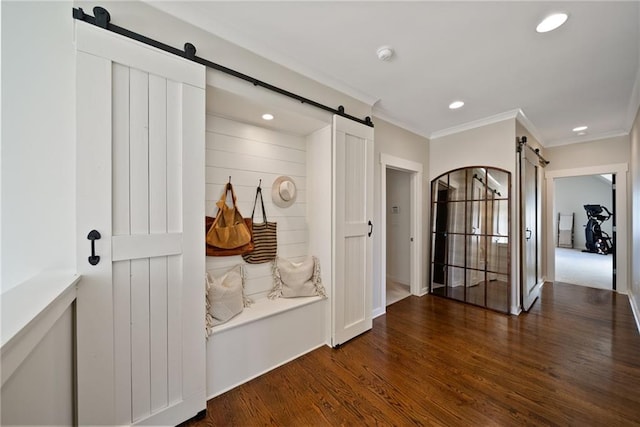 interior space with recessed lighting, ornamental molding, a barn door, and wood finished floors