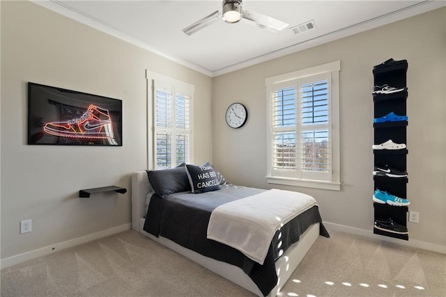 carpeted bedroom with visible vents, baseboards, ornamental molding, and a ceiling fan