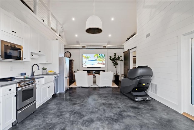 kitchen featuring a barn door, finished concrete floors, appliances with stainless steel finishes, and white cabinets