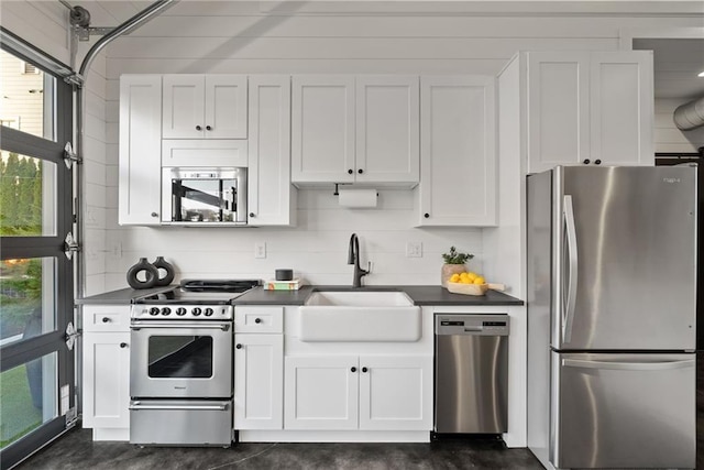 kitchen with dark countertops, appliances with stainless steel finishes, white cabinetry, and a sink