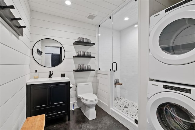 bathroom with toilet, stacked washer and clothes dryer, concrete floors, and a stall shower