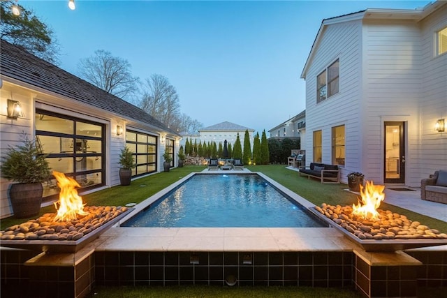 pool featuring a fire pit, a lawn, and a patio area