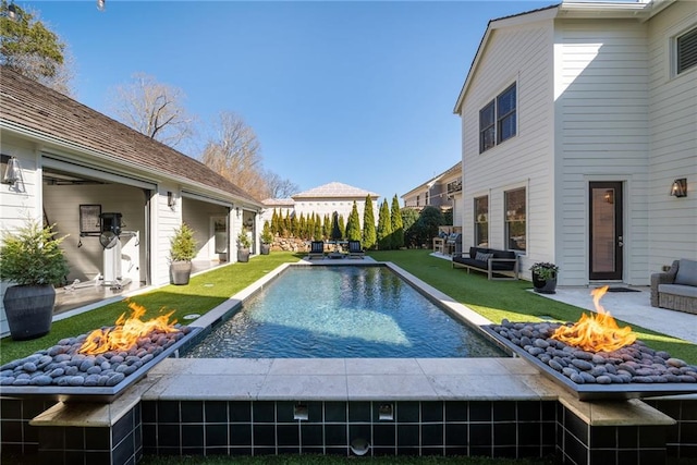 view of pool with a lawn, a fire pit, a patio, and a fenced in pool