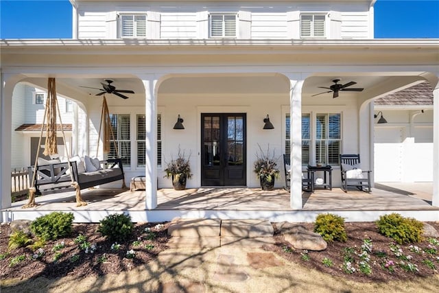 entrance to property featuring french doors, covered porch, a garage, an outdoor hangout area, and ceiling fan