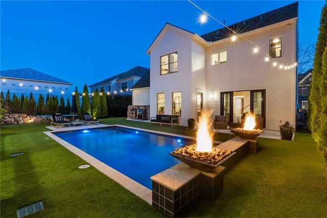 view of swimming pool featuring a fenced in pool, a fire pit, fence, a lawn, and a patio