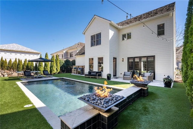 back of property with an outdoor living space with a fire pit, a patio, and a yard