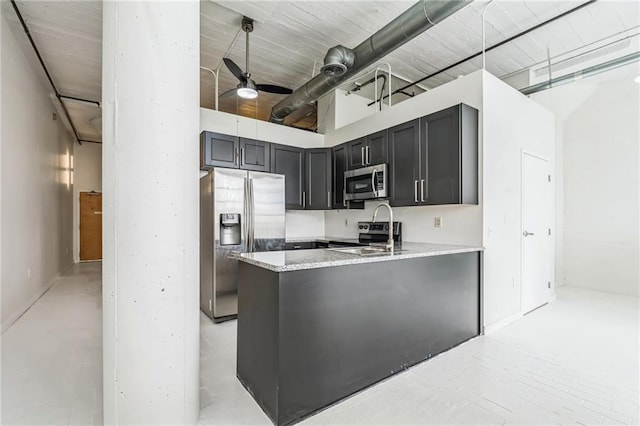 881 Memorial Dr SE Unit 307, Atlanta, GA 30316 - kitchen with appliances with stainless steel finishes, light stone counters, ceiling fan, a peninsula, and dark cabinetry