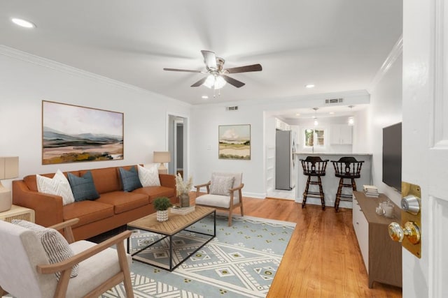 living room with ceiling fan, ornamental molding, and light hardwood / wood-style floors