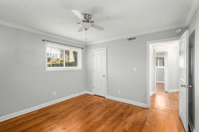 unfurnished bedroom featuring ceiling fan, a closet, crown molding, and wood-type flooring