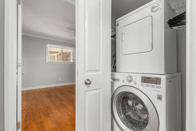 washroom with ornamental molding, stacked washer / dryer, and wood-type flooring