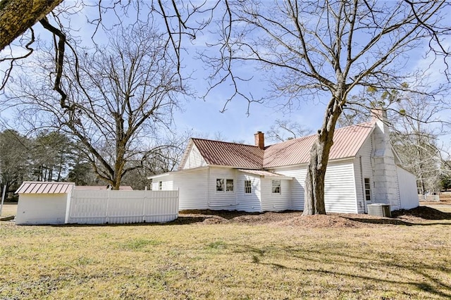 rear view of property with a lawn and central air condition unit