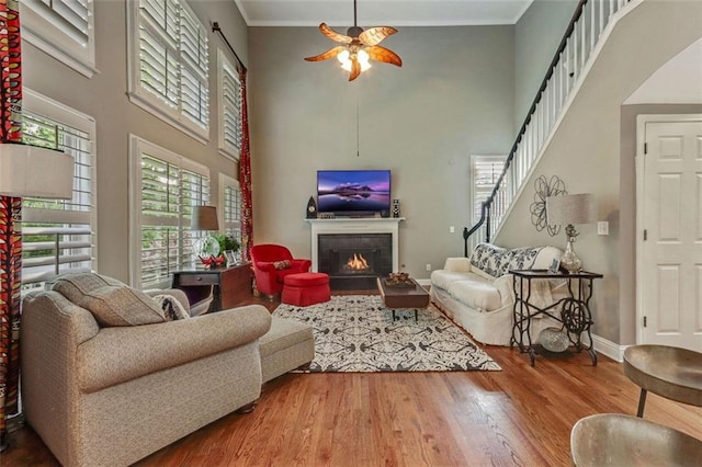 2073 Woodside Park Dr, Woodstock, GA 30188 - living room featuring a high ceiling, ceiling fan, healthy amount of natural light, a warm lit fireplace, and wood finished floors