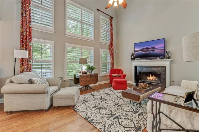 2073 Woodside Park Dr, Woodstock, GA 30188 - living area featuring wood finished floors, a tile fireplace, a towering ceiling, and ceiling fan