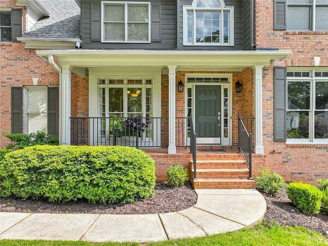 2073 Woodside Park Dr, Woodstock, GA 30188 - view of exterior entry featuring brick siding, a porch, and a shingled roof