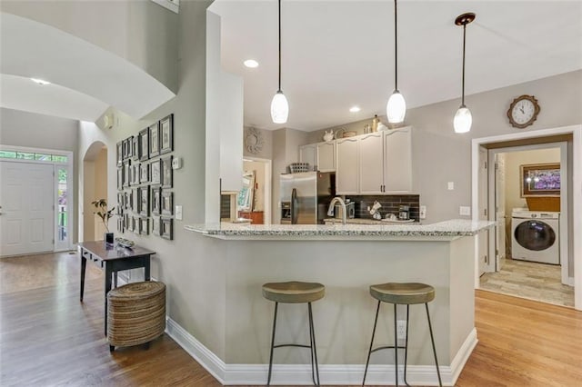 2073 Woodside Park Dr, Woodstock, GA 30188 - kitchen with stainless steel refrigerator with ice dispenser, arched walkways, light wood finished floors, white cabinetry, and tasteful backsplash