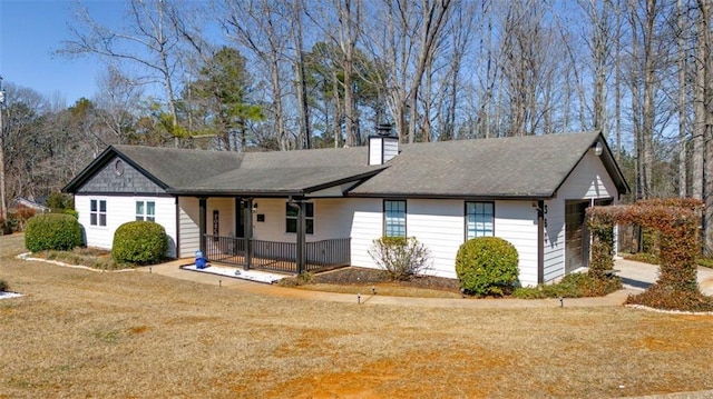 ranch-style home featuring a porch, a chimney, and a front yard