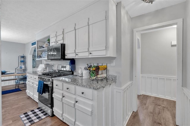 kitchen with light wood finished floors, white cabinets, light stone counters, stainless steel appliances, and open shelves