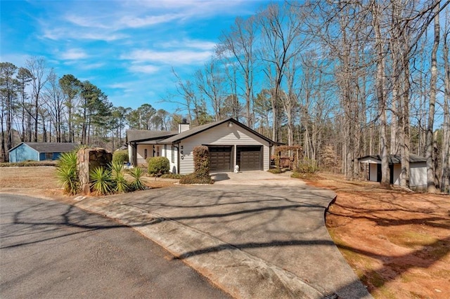 view of front of house featuring a garage, concrete driveway, and a chimney