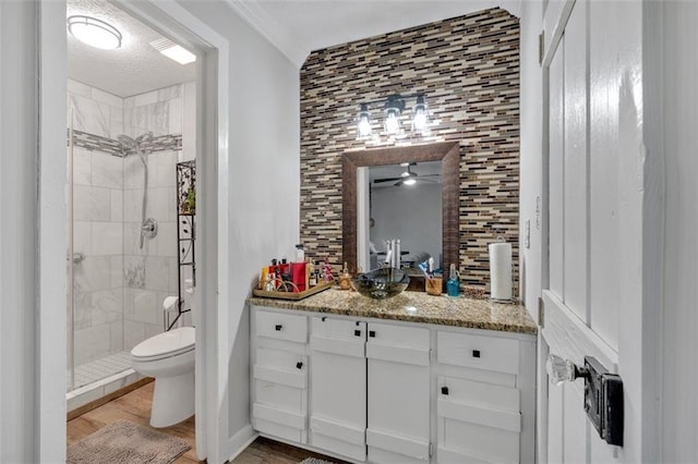 bathroom with toilet, wood finished floors, vanity, backsplash, and a shower stall