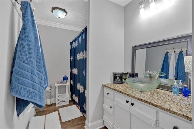 full bathroom with a textured ceiling, wood finished floors, vanity, baseboards, and ornamental molding