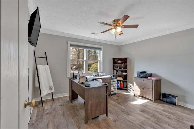 office area featuring a textured ceiling, ornamental molding, visible vents, and light wood-style floors