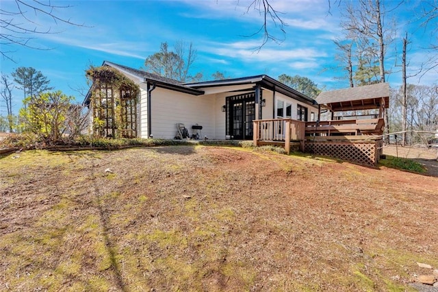 back of house featuring a deck and a lawn