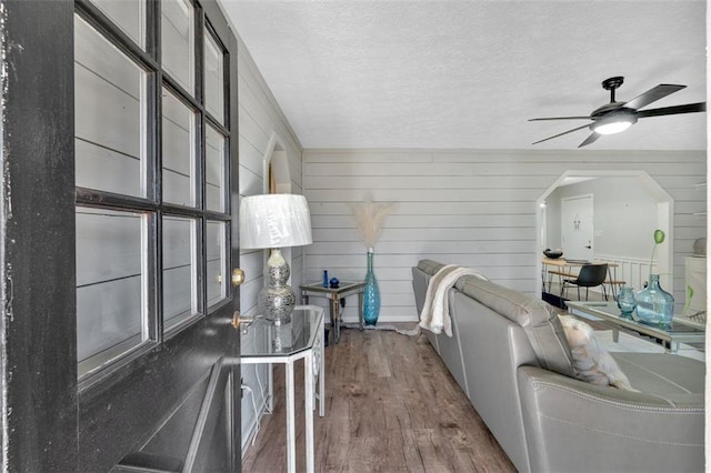 living area with a textured ceiling, a ceiling fan, and dark wood-type flooring