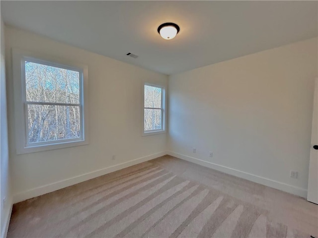 empty room with light colored carpet, visible vents, and baseboards