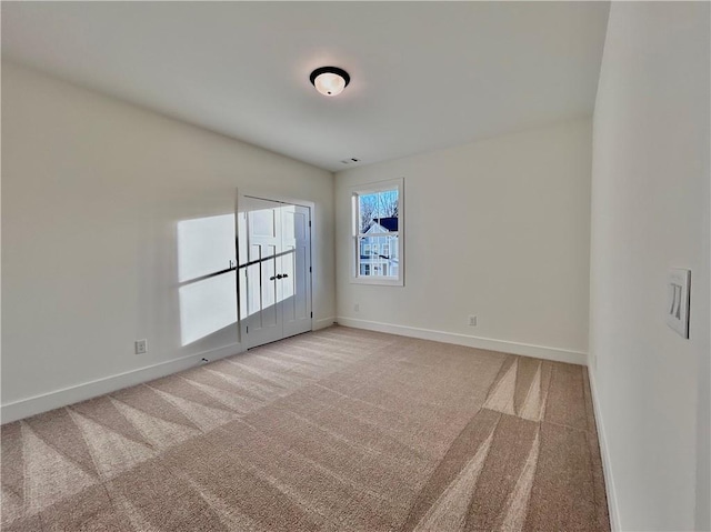 spare room featuring baseboards and light colored carpet