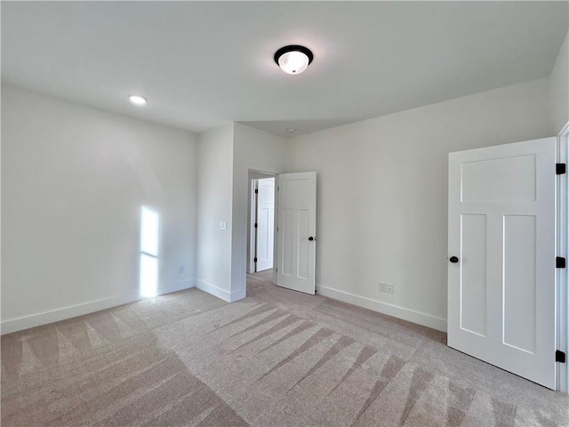 unfurnished room featuring baseboards and light colored carpet